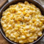 Easy creamed corn served in a rustic bowl, made with sweet corn kernels simmered in a creamy sauce, garnished with fresh herbs.