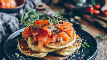 “Mini blinis topped with smoked salmon, cream cheese, and fresh dill served on a platter.”