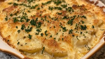 Creamy potato gratin baked golden brown in a casserole dish, with thinly sliced potatoes layered in a rich cream sauce, topped with melted cheese and fresh herbs.