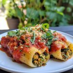 Vegan stuffed shells baked in a casserole dish, filled with creamy tofu ricotta, spinach, and herbs, topped with marinara sauce and melted dairy-free cheese.