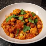 Cauliflower and Chickpea Curry Recipe served in a bowl with fluffy rice, rich golden curry sauce, fresh cilantro, and warm spices.