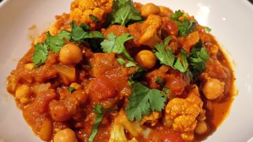 Cauliflower and Chickpea Curry Recipe served in a bowl with fluffy rice, rich golden curry sauce, fresh cilantro, and warm spices.