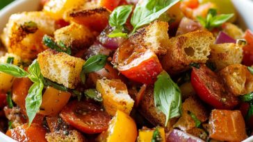 Rustic Italian Panzanella salad with juicy tomatoes, toasted bread cubes, cucumbers, red onions, and fresh basil served in a bowl.