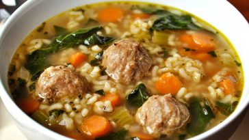 Italian wedding soup served in a rustic bowl with tender meatballs, fresh spinach, carrots, and tiny pasta in a savory broth, garnished with Parmesan cheese.