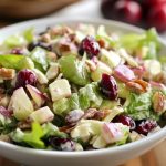 Cranberry Waldorf salad with fresh cranberries, apples, grapes, celery, and walnuts tossed in a creamy dressing, served in a festive bowl.