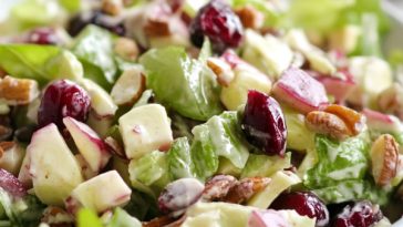 Cranberry Waldorf salad with fresh cranberries, apples, grapes, celery, and walnuts tossed in a creamy dressing, served in a festive bowl.