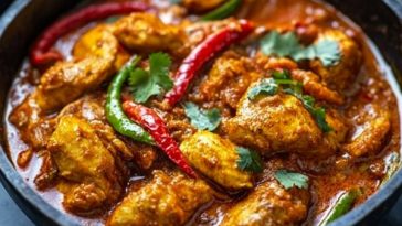 Spicy chicken jalfrezi curry with tender chicken pieces, bell peppers, onions, and tomatoes simmered in a rich sauce, served with rice.