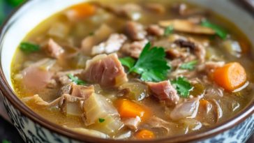 Instant Pot leftover hambone soup served in a rustic bowl with tender ham, beans, carrots, celery, and potatoes simmered in a savory broth, garnished with parsley.