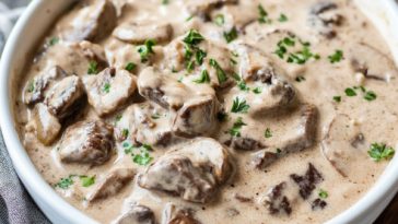 Slow Cooker Beef Stroganoff Stew Recipe with tender beef chunks, creamy sauce, mushrooms, and fresh herbs served over egg noodles.