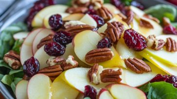 Apple cranberry pecan salad served in a large bowl with crisp apple slices, dried cranberries, crunchy pecans, mixed greens, and a light vinaigrette dressing.