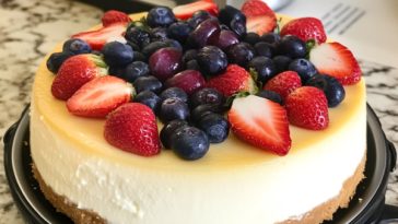Perfect Instant Pot New York cheesecake with a golden crust, creamy filling, and topped with fresh berries, served on a cake stand.
