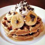 Healthy protein waffles stacked on a plate, golden brown and fluffy, topped with fresh berries, Greek yogurt, and a drizzle of honey.