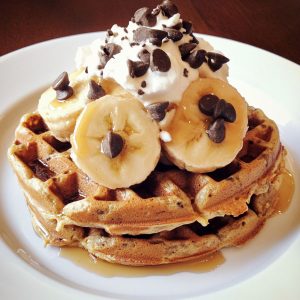 Healthy protein waffles stacked on a plate, golden brown and fluffy, topped with fresh berries, Greek yogurt, and a drizzle of honey.