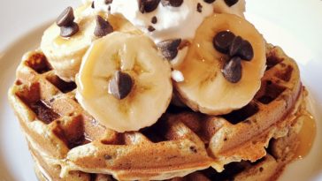 Healthy protein waffles stacked on a plate, golden brown and fluffy, topped with fresh berries, Greek yogurt, and a drizzle of honey.