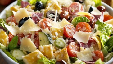 Fresh Mega Italian Salad with colorful vegetables, olives, cheese, and herbs served in a large bowl