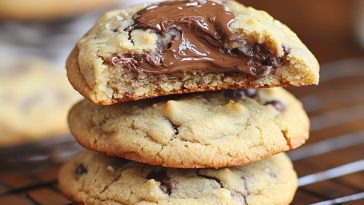 Nutella Stuffed Cookies Recipe with golden-brown cookies filled with gooey Nutella chocolate hazelnut spread, stacked on a plate.