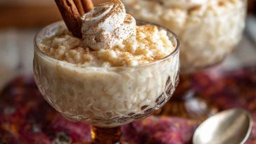 “A creamy rice pudding topped with ground cinnamon and garnished with a cinnamon stick in a serving bowl.”