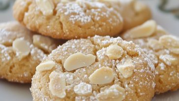 “Golden Cretan almond cookies arranged on a plate, lightly dusted with powdered sugar.”