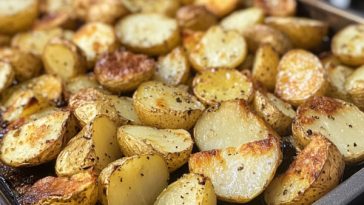 Salt and vinegar roasted potatoes baked until golden and crispy, served on a tray with fresh herbs and a dipping sauce on the side.