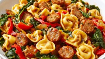 Sausage and tortellini stir-fry served in a skillet with golden-browned sausage slices, cheese-filled tortellini, colorful bell peppers, onions, and fresh parsley garnish.
