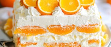 Orange dreamsicle icebox cake layered with vanilla wafers, creamy orange filling, and whipped topping, chilled in a baking dish and garnished with orange slices.