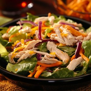 Chinese chicken salad served in a large bowl with shredded chicken, crisp cabbage, carrots, crunchy noodles, sesame seeds, and tangy Asian dressing.