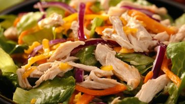 Chinese chicken salad served in a large bowl with shredded chicken, crisp cabbage, carrots, crunchy noodles, sesame seeds, and tangy Asian dressing.