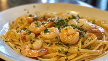 Shrimp scampi with linguini pasta tossed in a garlic butter sauce, garnished with fresh parsley and lemon wedges, served in a white bowl.