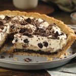 Chocolate crème cookie pie with a crunchy cookie crust, creamy chocolate filling, and whipped topping, garnished with chocolate shavings and cookie crumbles.