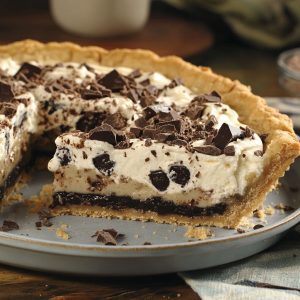 Chocolate crème cookie pie with a crunchy cookie crust, creamy chocolate filling, and whipped topping, garnished with chocolate shavings and cookie crumbles.