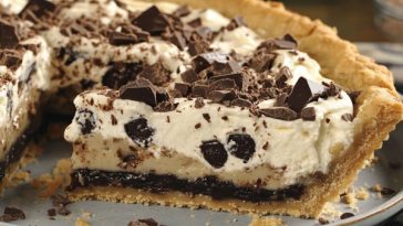 Chocolate crème cookie pie with a crunchy cookie crust, creamy chocolate filling, and whipped topping, garnished with chocolate shavings and cookie crumbles.