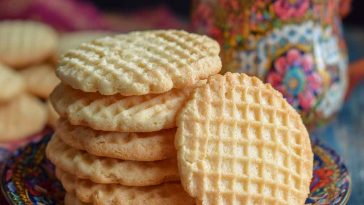 Golden vanilla wafer cookies stacked neatly on a plate, with a light, crisp texture and sweet aroma.