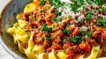 Classic Marcella Hazan’s Bolognese sauce simmering in a pot with ground beef, tomatoes, milk, and aromatic vegetables.