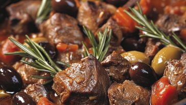 Rustic lamb stew with rosemary and olives served in a deep bowl, garnished with fresh herbs and crusty bread on the side.