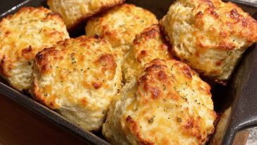 Golden butter swim biscuits baked in a skillet, with crispy edges and fluffy centers glistening with melted butter.