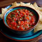 “A vibrant bowl of homemade salsa with fresh tomatoes, onions, cilantro, and jalapeños served with tortilla chips.”