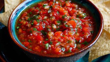 “A vibrant bowl of homemade salsa with fresh tomatoes, onions, cilantro, and jalapeños served with tortilla chips.”