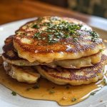 “Golden, crispy German potato pancakes served with sour cream and fresh herbs on a rustic plate.”