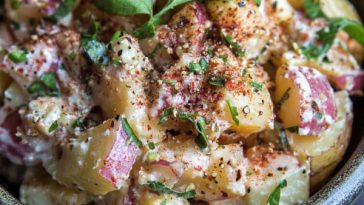 “A vibrant potato salad tossed with sumac, fresh herbs, and olive oil, served in a rustic bowl.”
