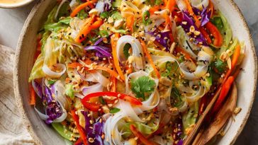 Colorful spring roll salad with rice noodles, vegetables, and spicy ginger dressing in a bowl.