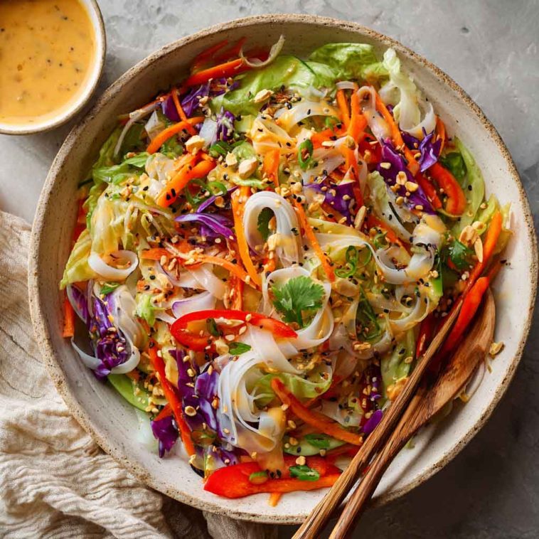 Colorful spring roll salad with rice noodles, vegetables, and spicy ginger dressing in a bowl.