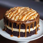 Layered chocolate fudge cake with salted caramel buttercream frosting and caramel drizzle on top.