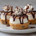 Mini tiramisu cookie cups filled with creamy mascarpone, dusted with cocoa powder, and topped with chocolate shavings, served on a dessert tray.