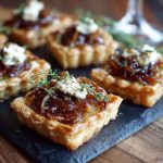 Irresistible caramelized onion and goat cheese tarts with golden puff pastry, creamy goat cheese filling, and sweet caramelized onions, garnished with fresh thyme.