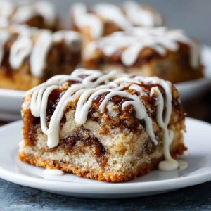Cinnamon Roll Bliss Bars with swirled cinnamon filling, creamy glaze drizzle, and golden baked edges, served on a dessert tray.