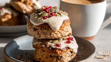 Golden breakfast protein biscuits stacked on a plate, filled with eggs, cheese, and sausage, ready to serve.
