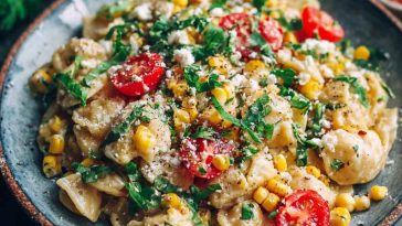 A colorful bowl of healthy street corn pasta salad with grilled corn, whole grain pasta, avocado, cilantro, and a creamy lime dressing.