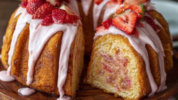 A slice of strawberry honeybun cake with swirls of cinnamon sugar, topped with creamy strawberry icing and fresh strawberry slices.