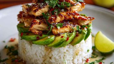Honey lime chicken & avocado rice stack layered with grilled chicken, fluffy rice, creamy avocado, and fresh cilantro, drizzled with honey lime glaze and served in a stacked presentation.