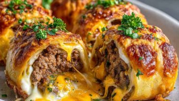 Golden garlic butter cheeseburger rollups sliced open to reveal melted cheese and seasoned beef, served with dipping sauces.